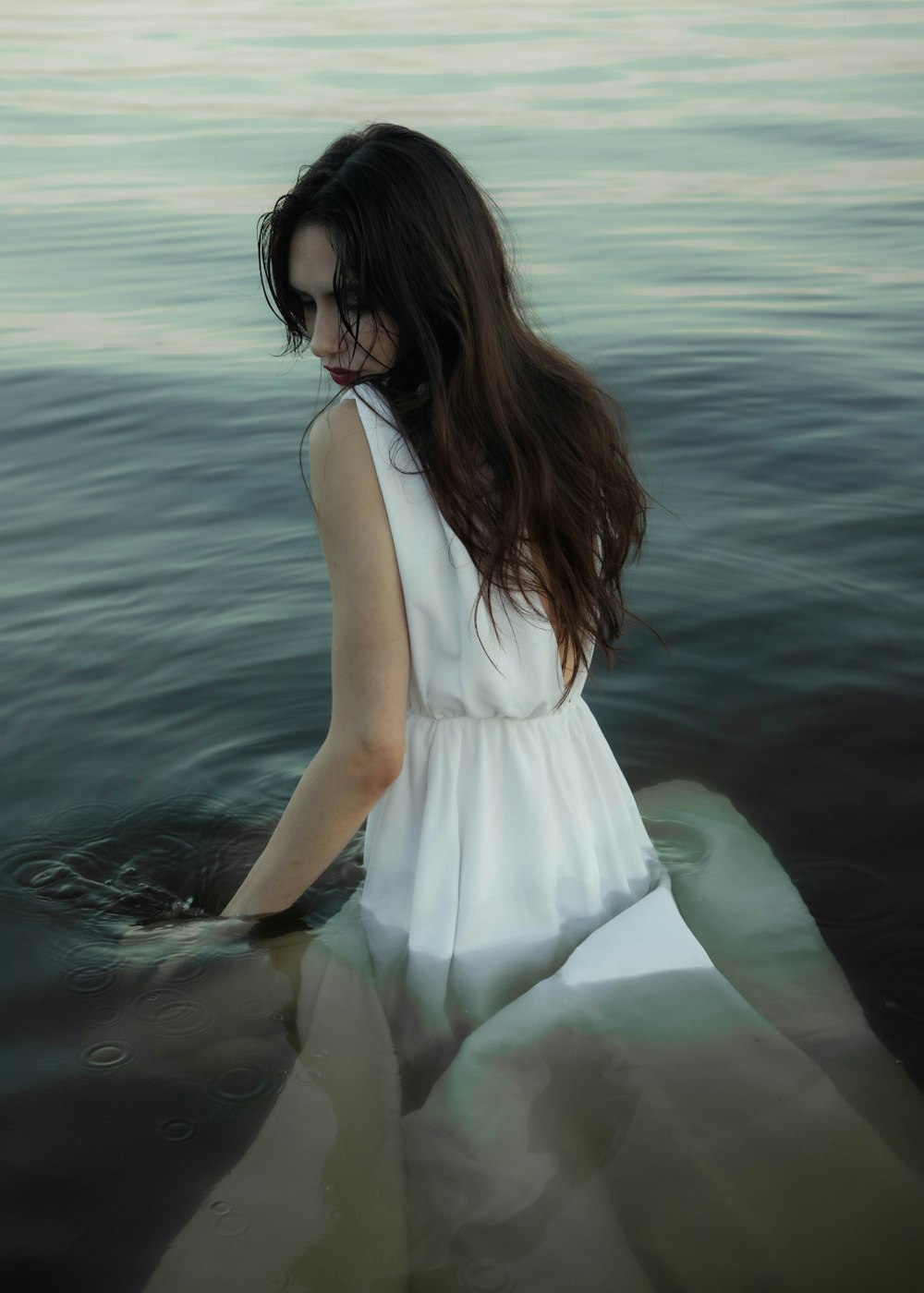 a woman in a white dress standing in the water
