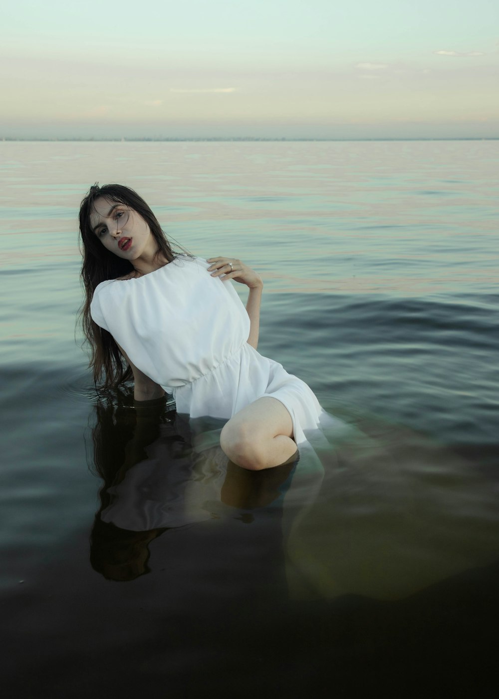 a woman in a white dress sitting in the water