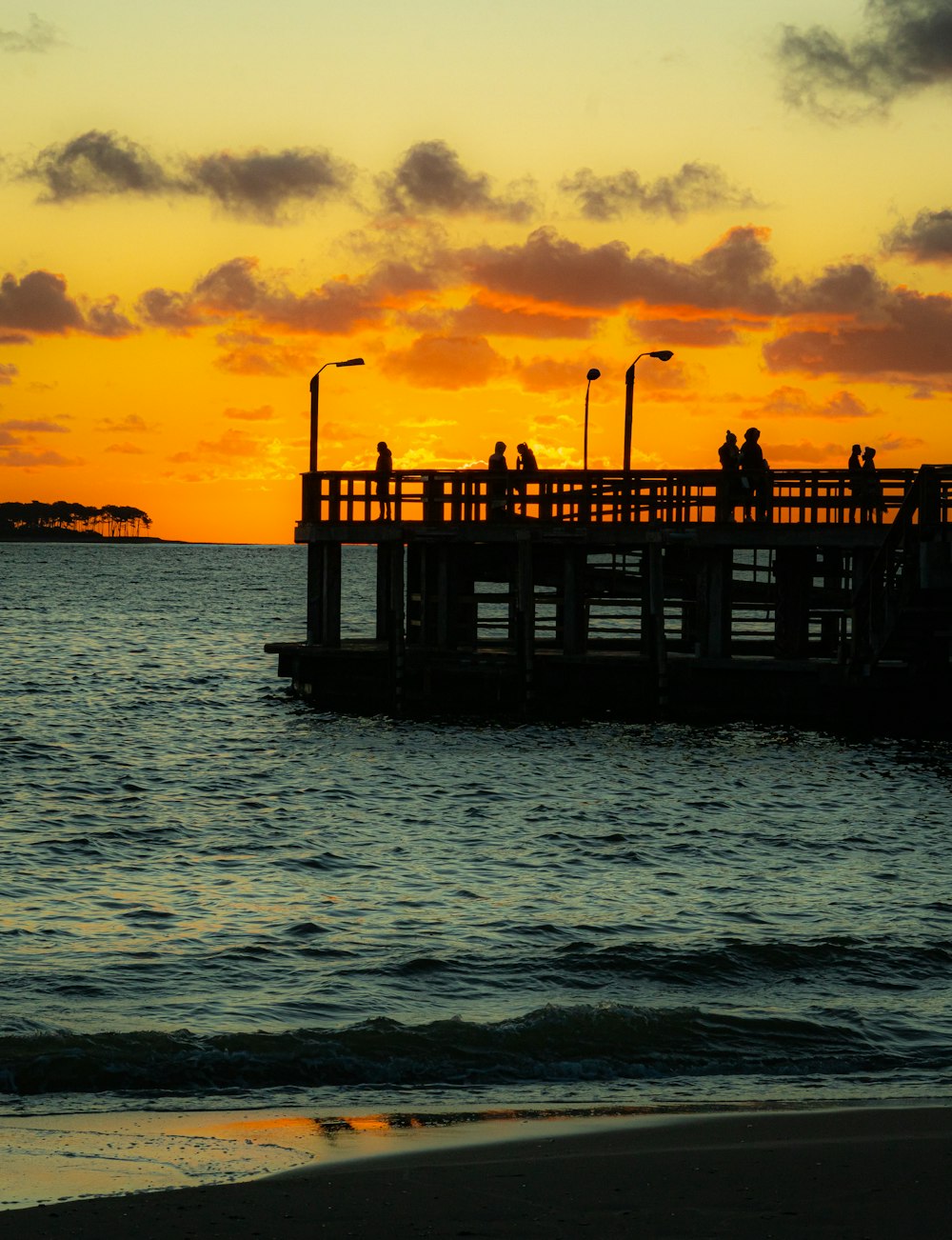 a pier with people standing on it at sunset