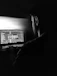 Smiling entrepreneur working on a laptop with futuristic digital overlays in a dark-themed workspace.