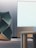 A modern interior space with a large, abstract geometric structure featuring dark green panels and gold outlines. Adjacent to it is a minimalist wooden table with rounded legs. In the background, a large white panel with a light wooden base appears to be part of the wall, suggesting a sleek, contemporary design theme.
