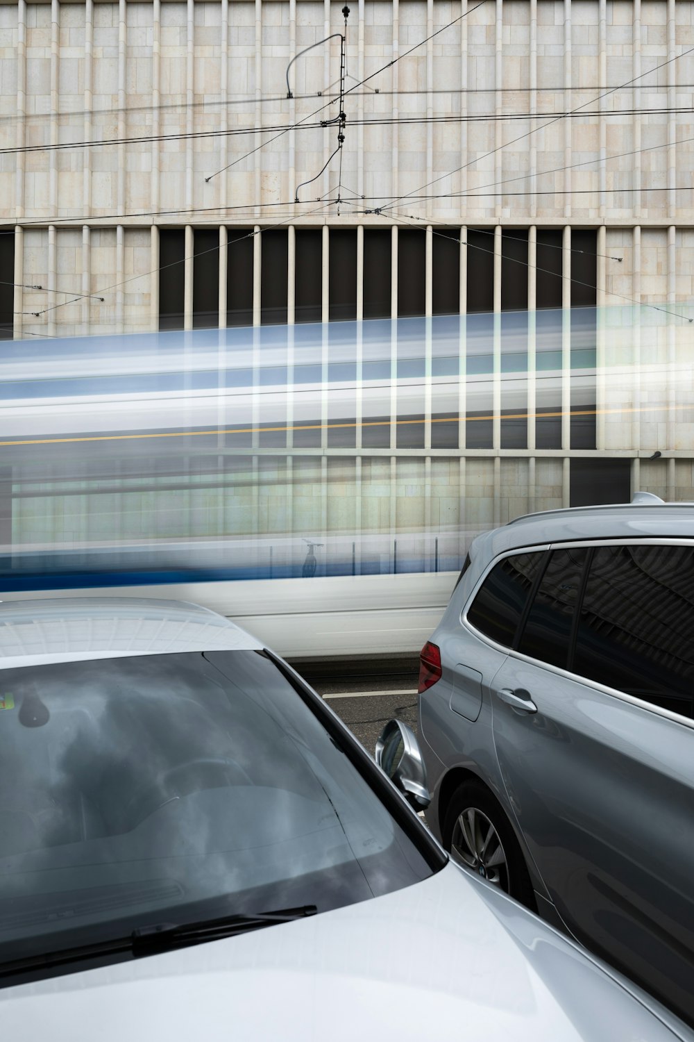 ein silbernes Auto, das neben einem Zug eine Straße entlang fährt