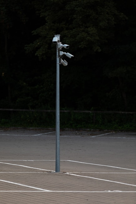 Close-up of a security camera mounted on a pole overlooking the parking lot