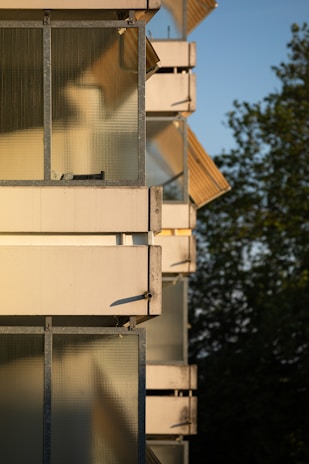 Evening scene of a balcony with illuminated glass panels and white aluminum railings casting gentle shadows.