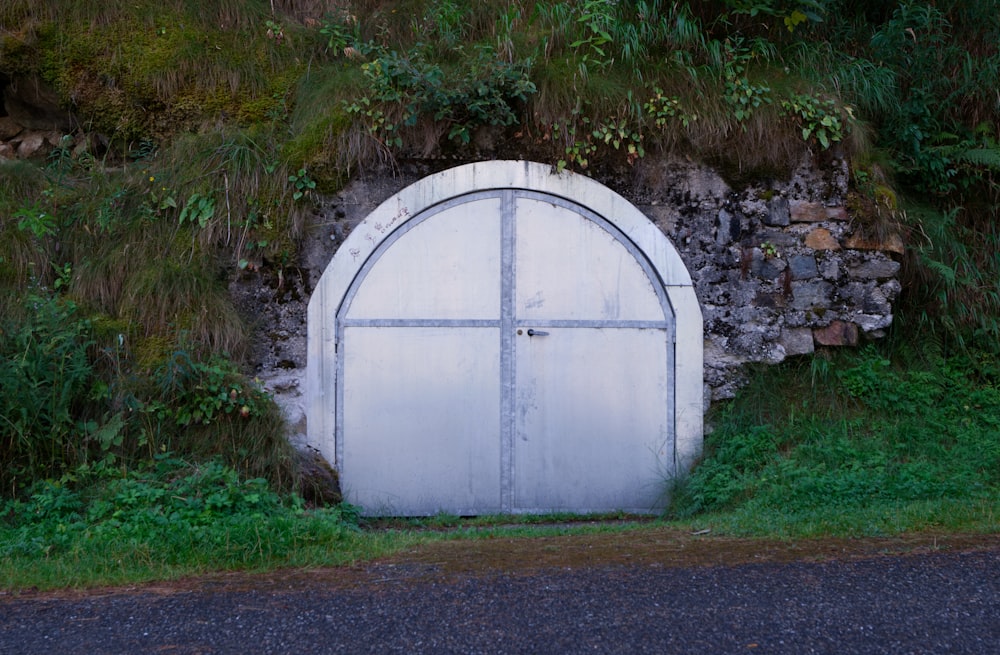 a large white door sitting in the middle of a lush green hillside