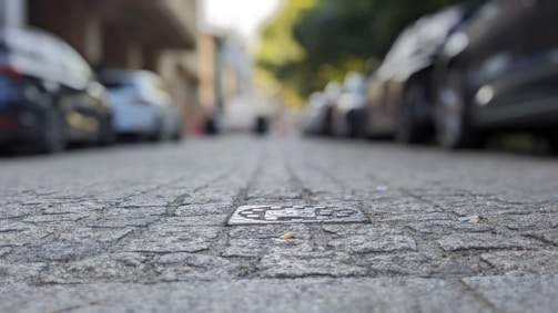 A close-up photo of a large pothole on a busy urban street with cars passing by.