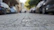 Close-up of a durable manhole cover installed on a city street with sunlight casting shadows.
