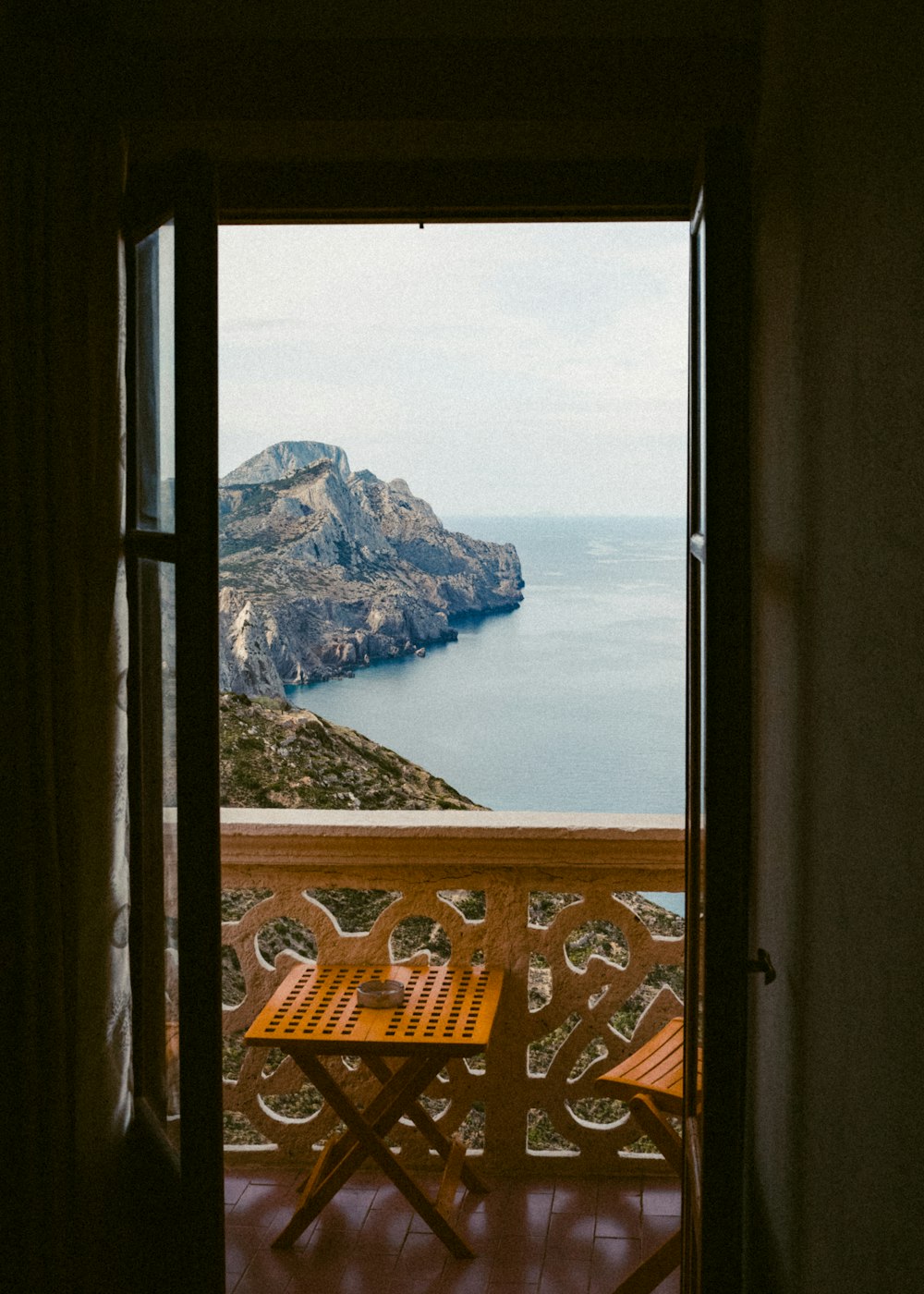 a balcony with a table and chairs looking out onto a body of water