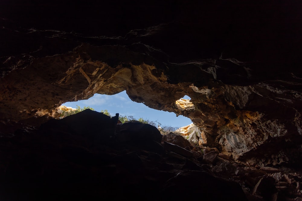 a person standing in a cave looking out at the sky