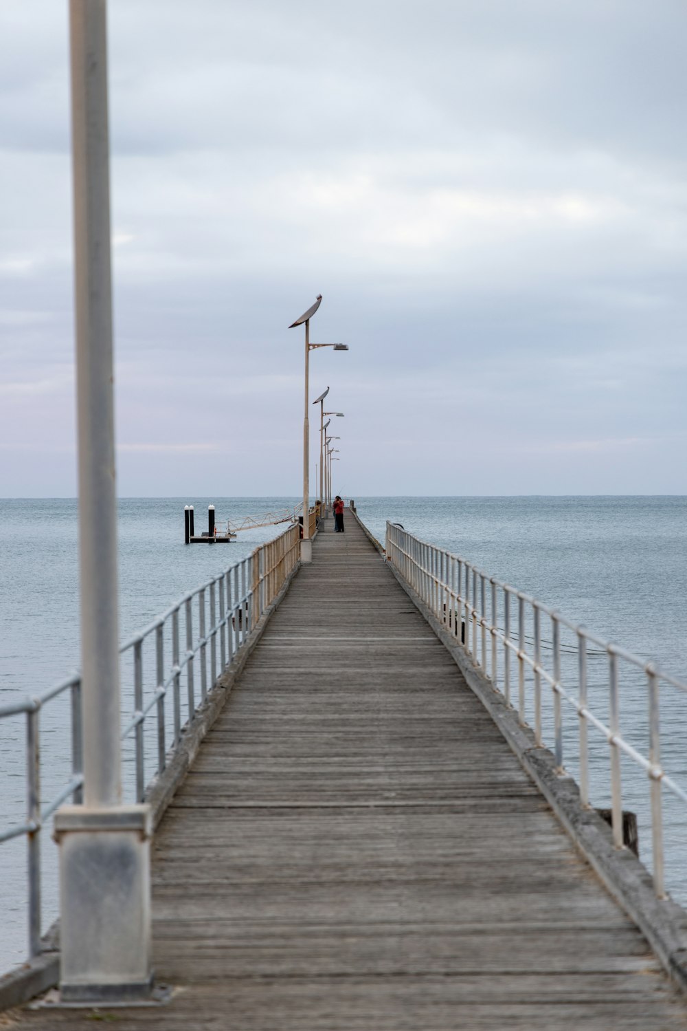 a pier with a light pole and a bench on the end of it