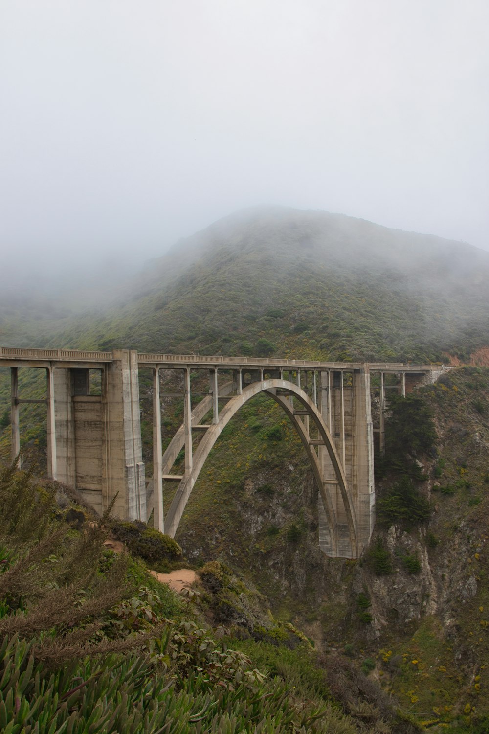 uma ponte que está sobre uma colina no nevoeiro
