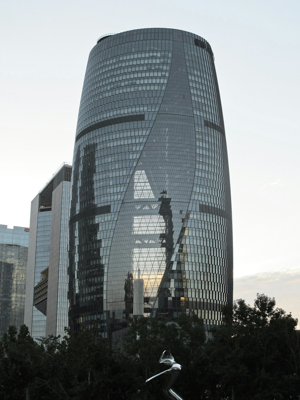 a tall glass building with a sculpture in front of it