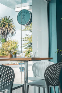 A sleek modern café table with a glass top and minimalist metal frame.