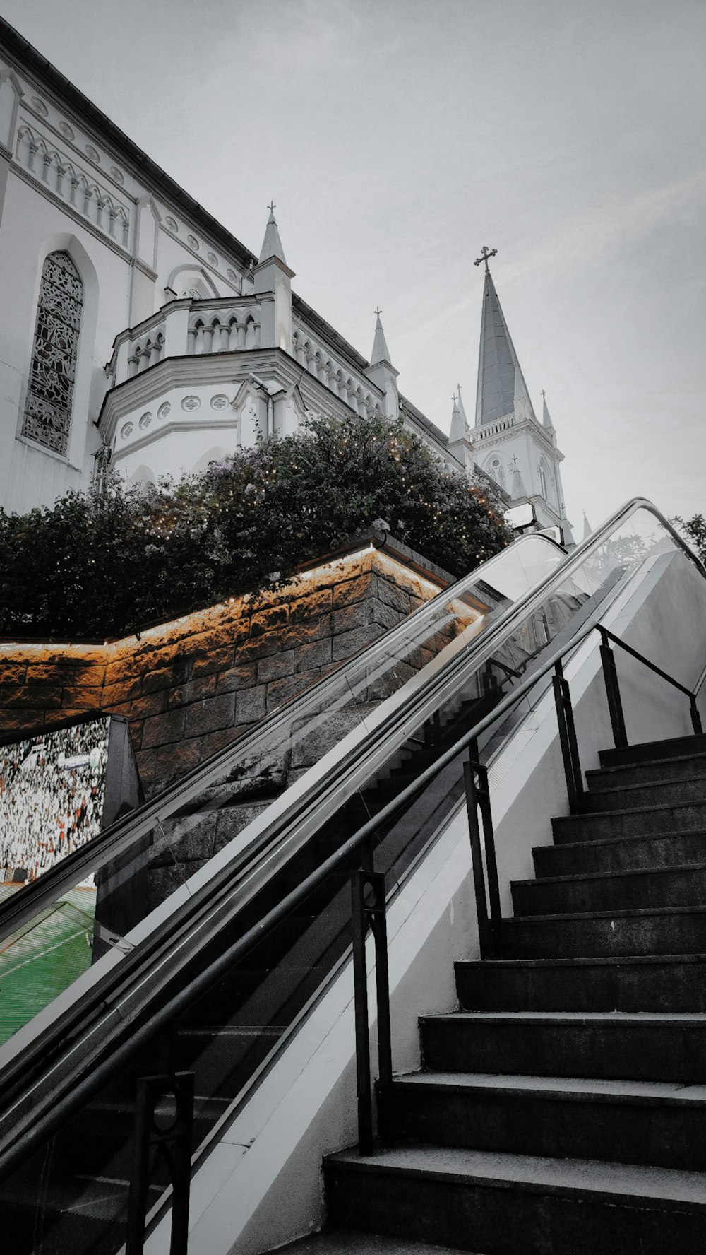 a black and white photo of an escalator with a church in the background