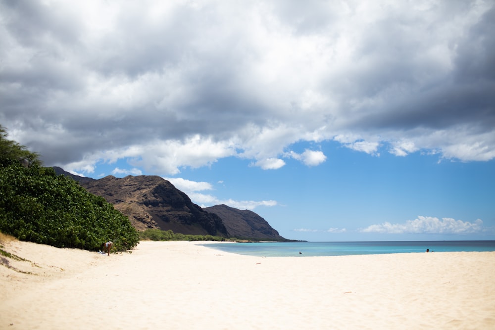 a sandy beach with a mountain in the background