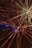 Bright, colorful laser beams radiate in various directions against a dark background, creating a dynamic and energetic composition. The beams converge towards the center and display a spectrum of colors including red, yellow, and hints of blue. The vibrant lights create a sense of movement and depth.