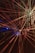Bright, colorful laser beams radiate in various directions against a dark background, creating a dynamic and energetic composition. The beams converge towards the center and display a spectrum of colors including red, yellow, and hints of blue. The vibrant lights create a sense of movement and depth.