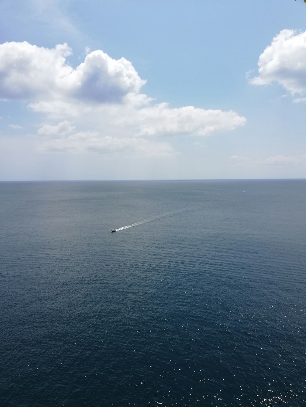 a boat in the middle of the ocean on a sunny day