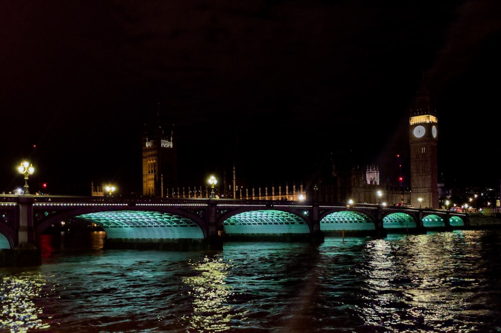 a bridge over a river with a clock tower in the background