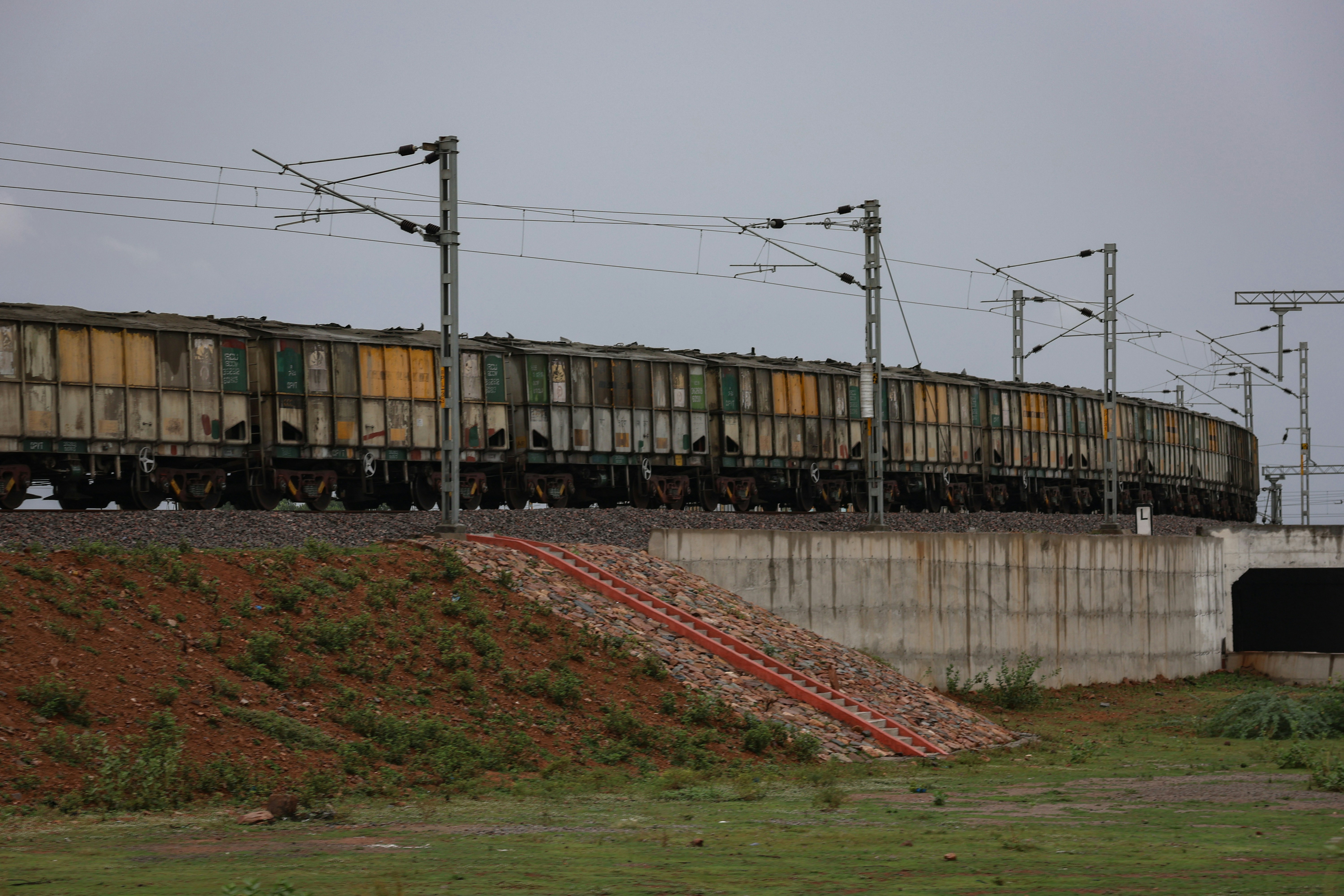 a train traveling down tracks next to a cement wall