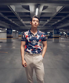 Confident lead standing in a clean parking garage pointing at a discreet indoor DAS unit mounted on a concrete beam.