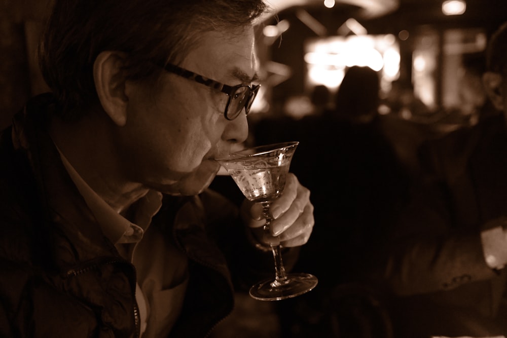 a man drinking from a wine glass in a bar