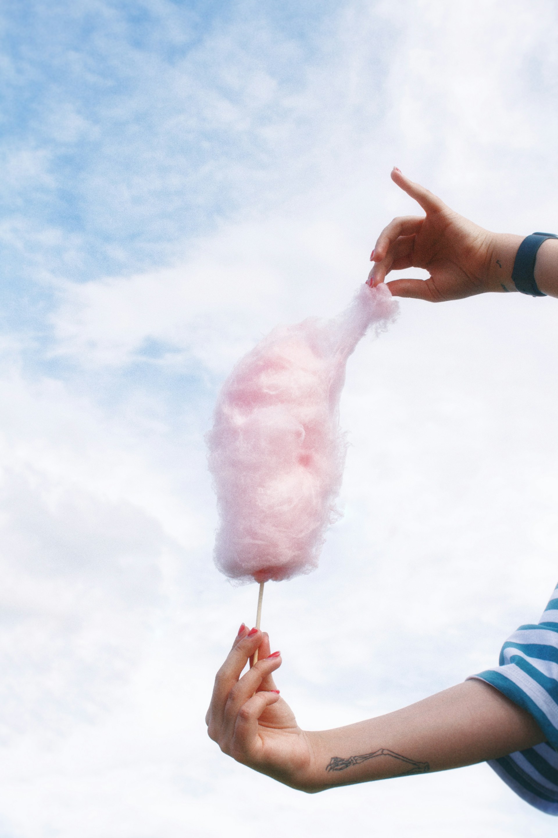 a person holding a pink cotton candy on a stick