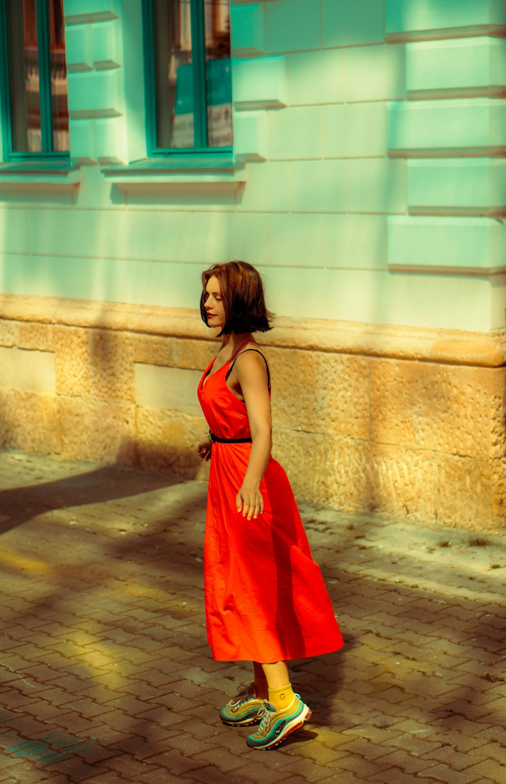 a woman in a red dress is walking down the street