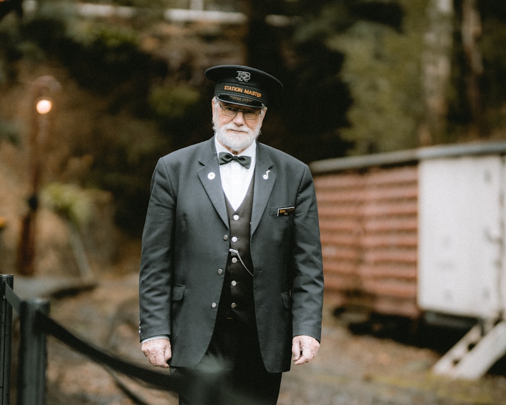 a man in a suit and bow tie standing next to a train