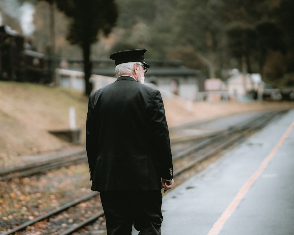 a man in a suit walking down a train track