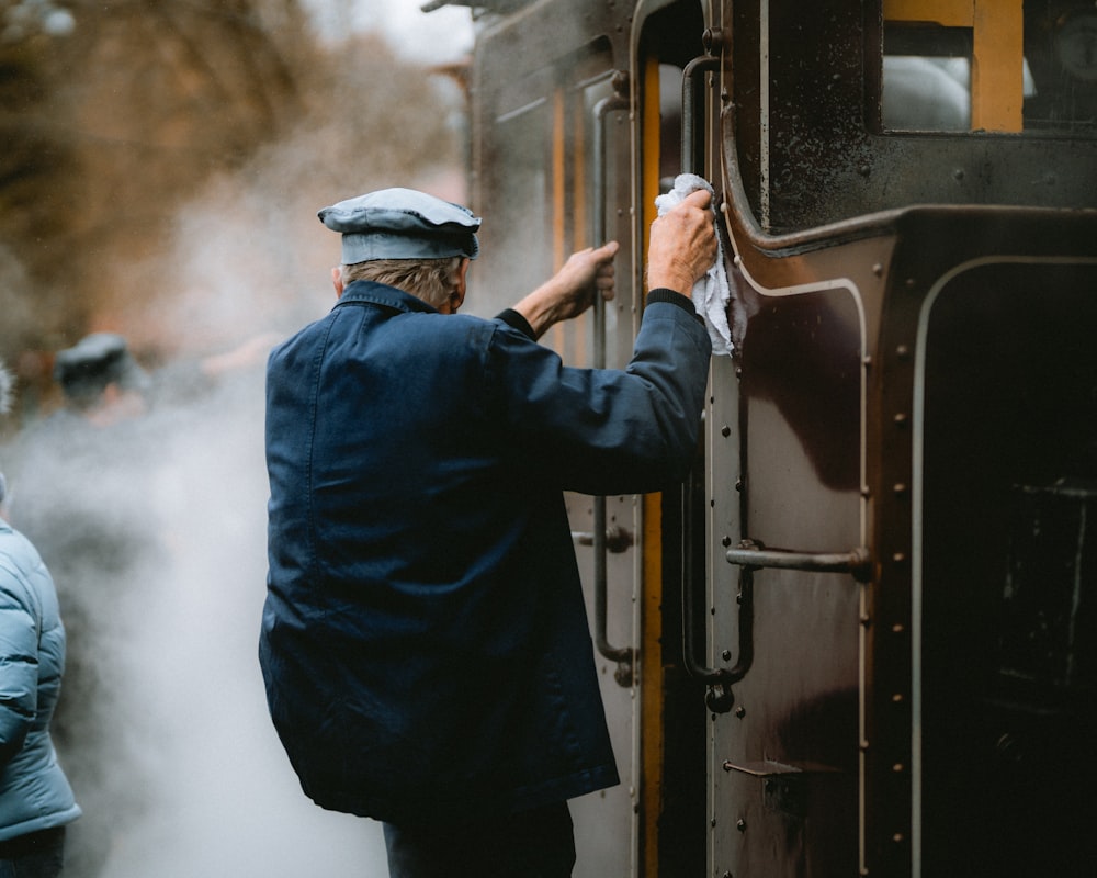 a man in a blue coat is opening a train door