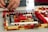 Close-up of hands assembling colorful LEGO bricks on a wooden table.
