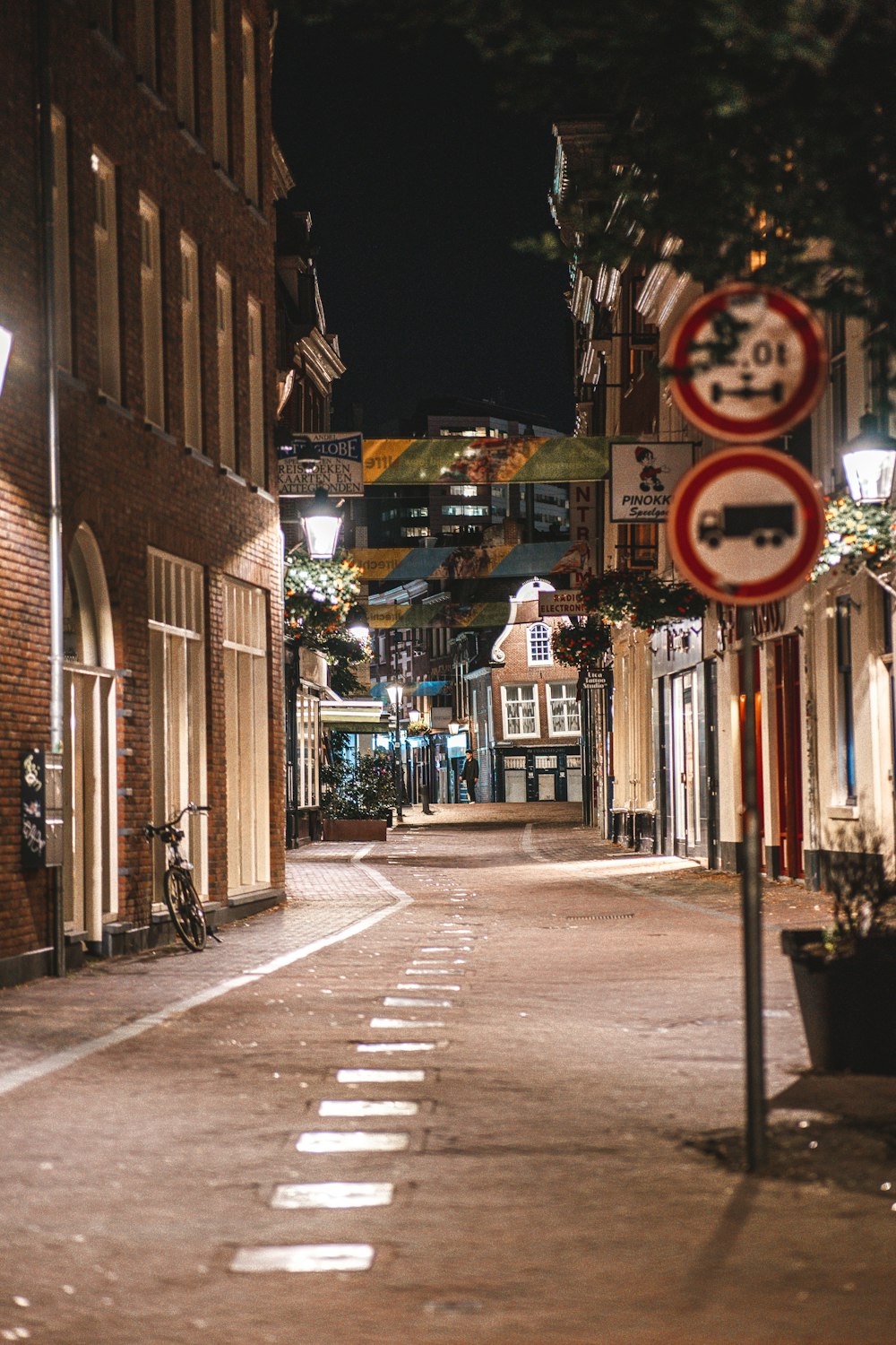 a city street at night with a bicycle parked on the side of the street