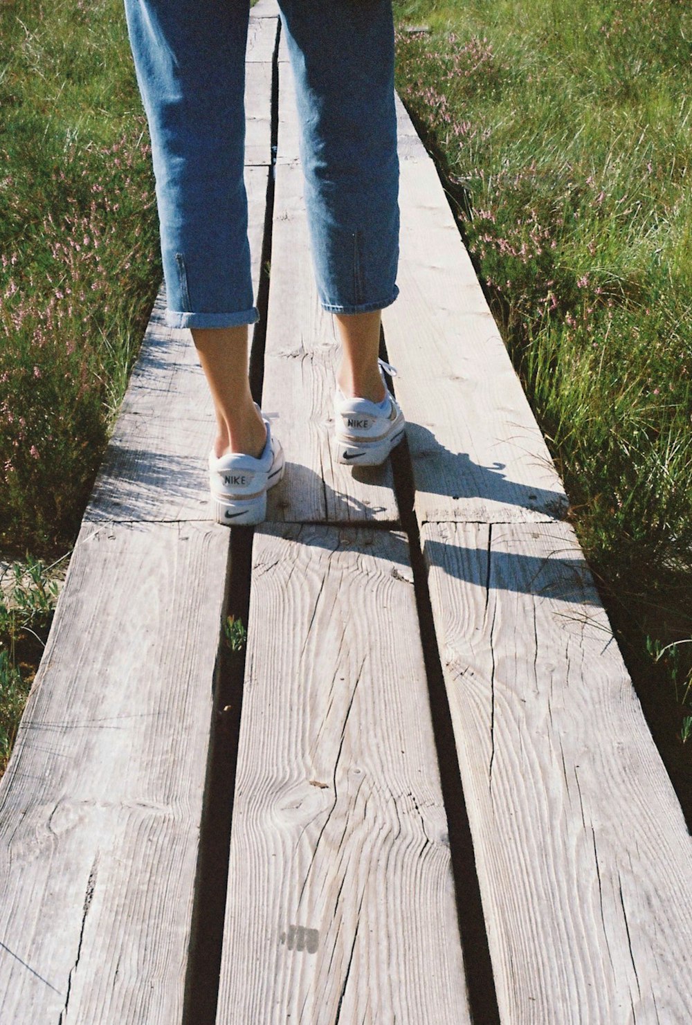 Una persona caminando por una pasarela de madera en la hierba
