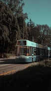 A sleek tram moving along a tree-lined urban street on a sunny day.