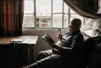 a man sitting in a chair holding a magnifying glass