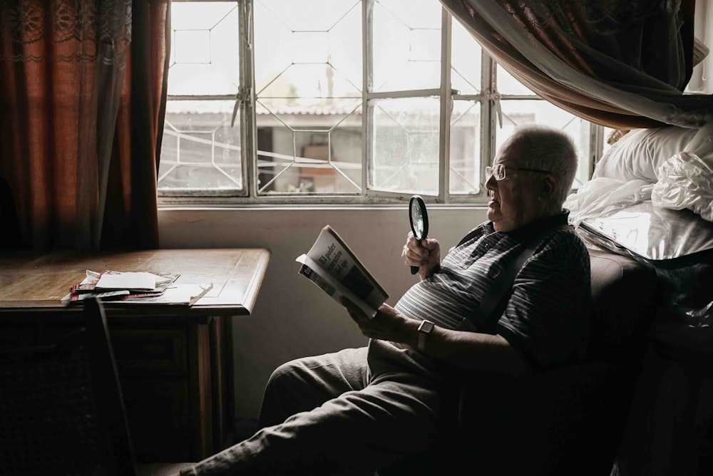 a man sitting in a chair holding a magnifying glass