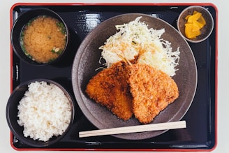a plate of food with rice, meat, and sauces