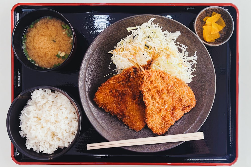 a plate of food with rice, meat, and sauces