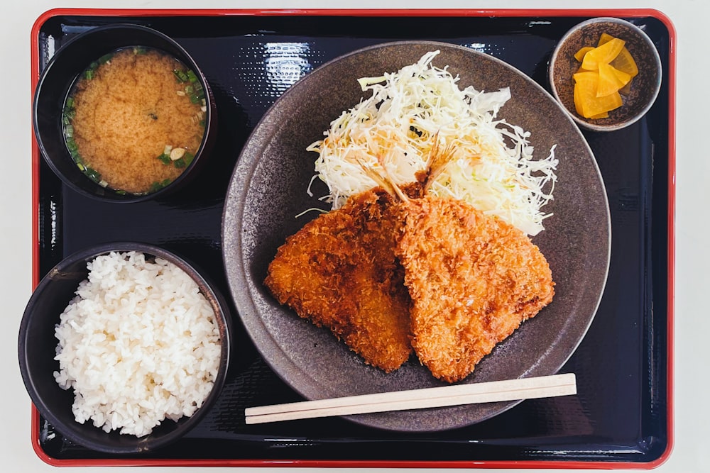ein Teller mit Essen mit Reis, Fleisch und Saucen