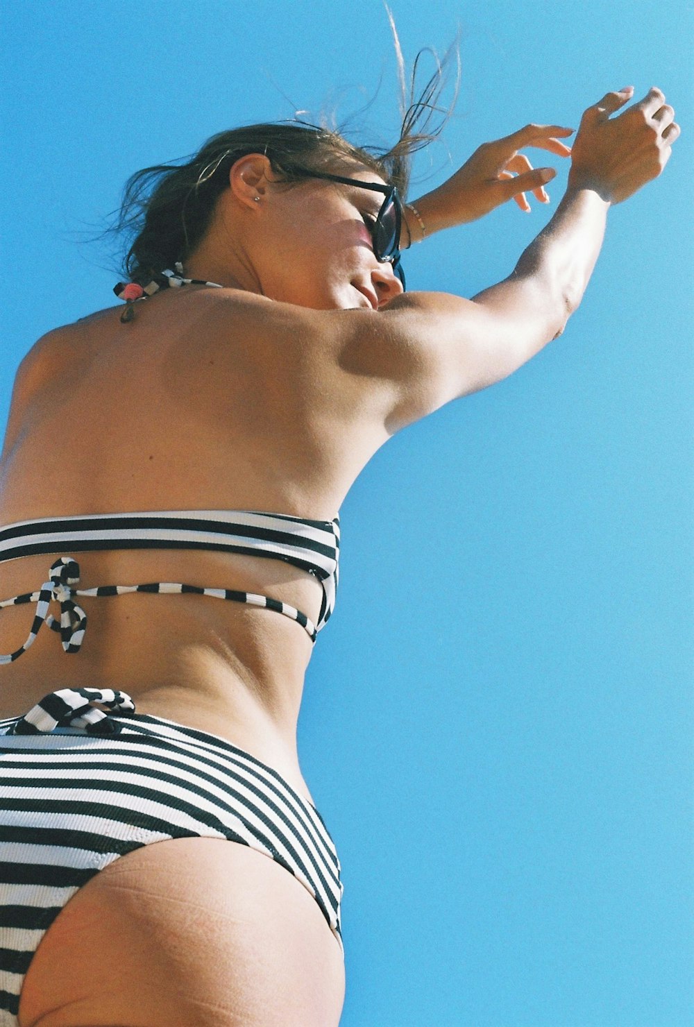 a woman in a striped bikini is flying a kite