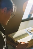 A person reading a thick law book with sunlight streaming through a window.
