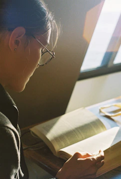 A caregiver reading the 'Voices of Care' book by a sunny window.