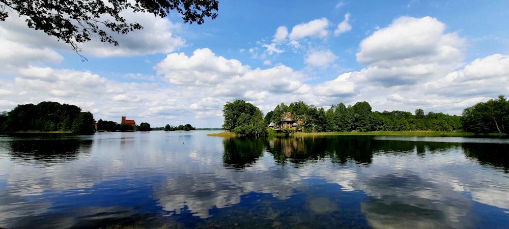 a body of water surrounded by trees and clouds