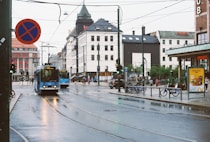 a blue bus driving down a street next to tall buildings