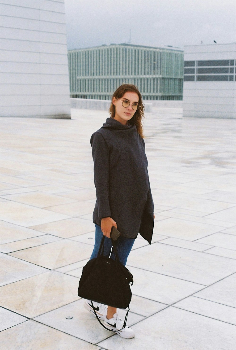 a woman standing on a tiled floor holding a handbag