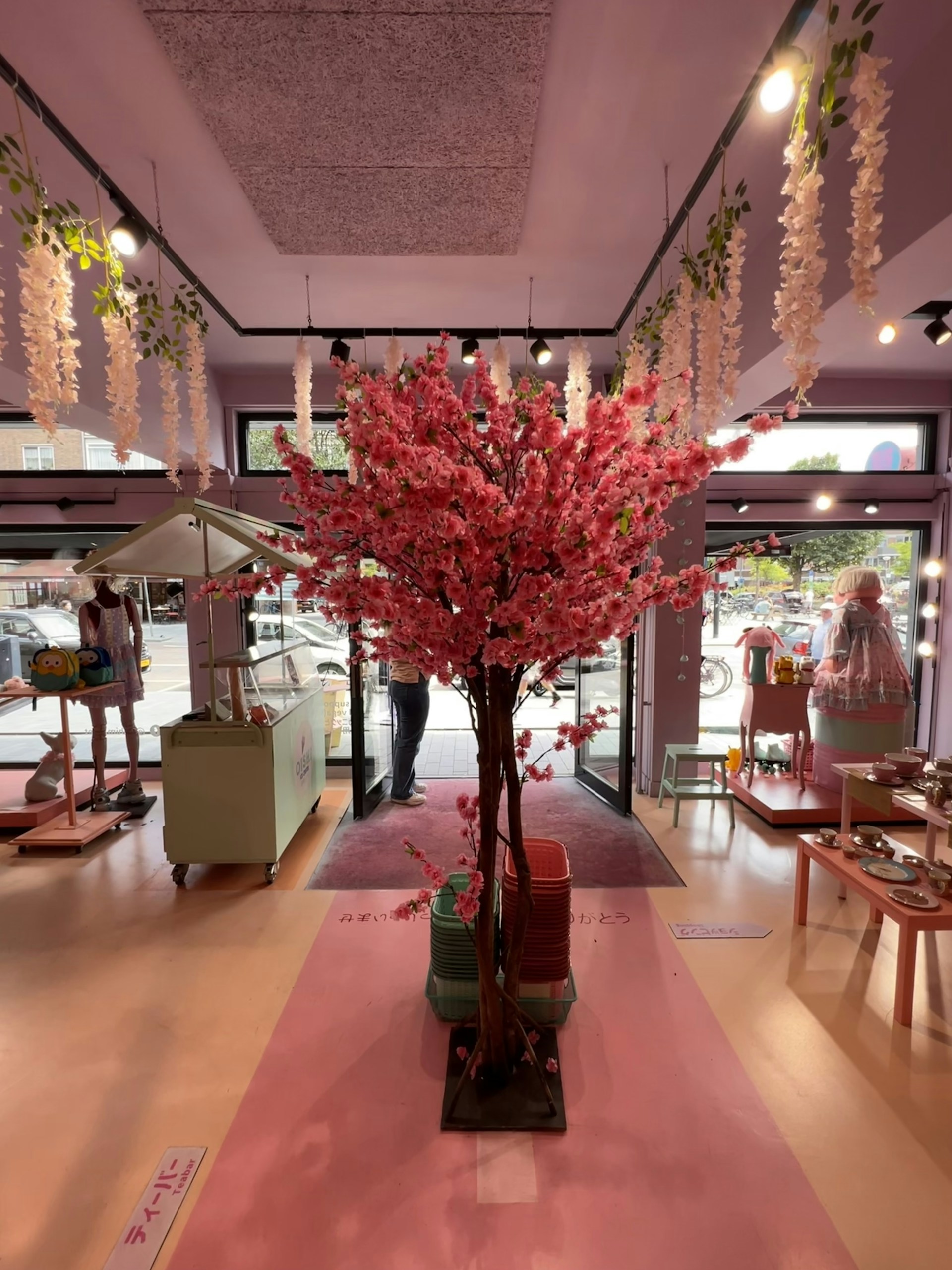 A cozy cafe interior adorned with pastel colors and cherry blossom decorations, inviting guests to relax.