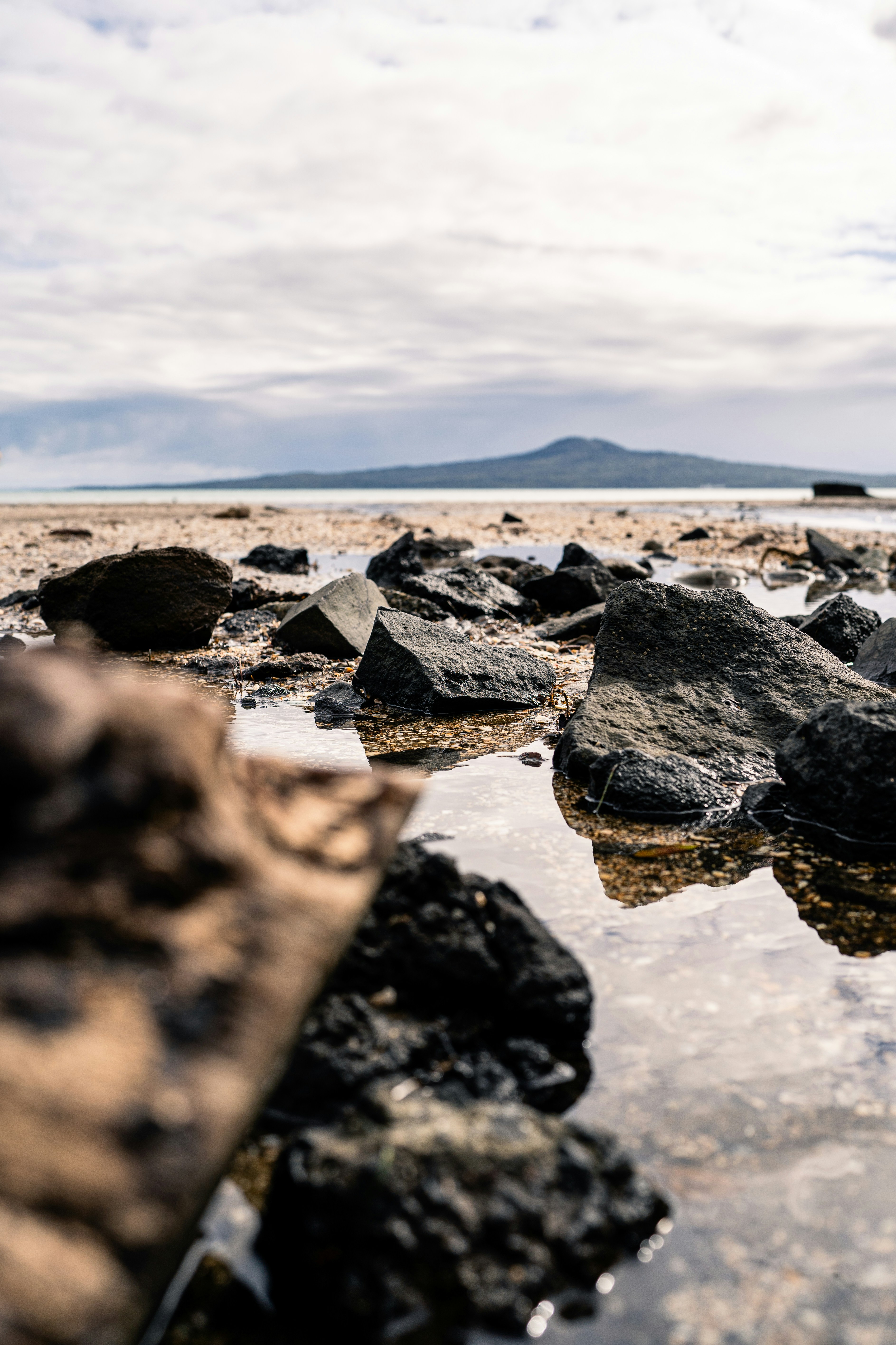 Rocks and water on a beach with a mountain in the background photo ...