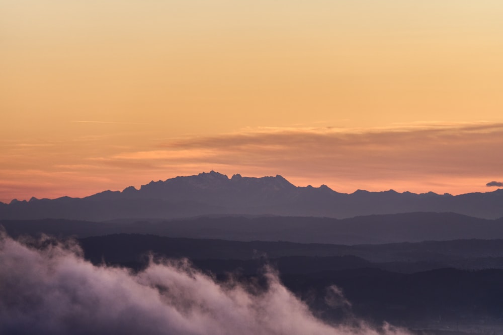 a view of a mountain range with clouds in the foreground