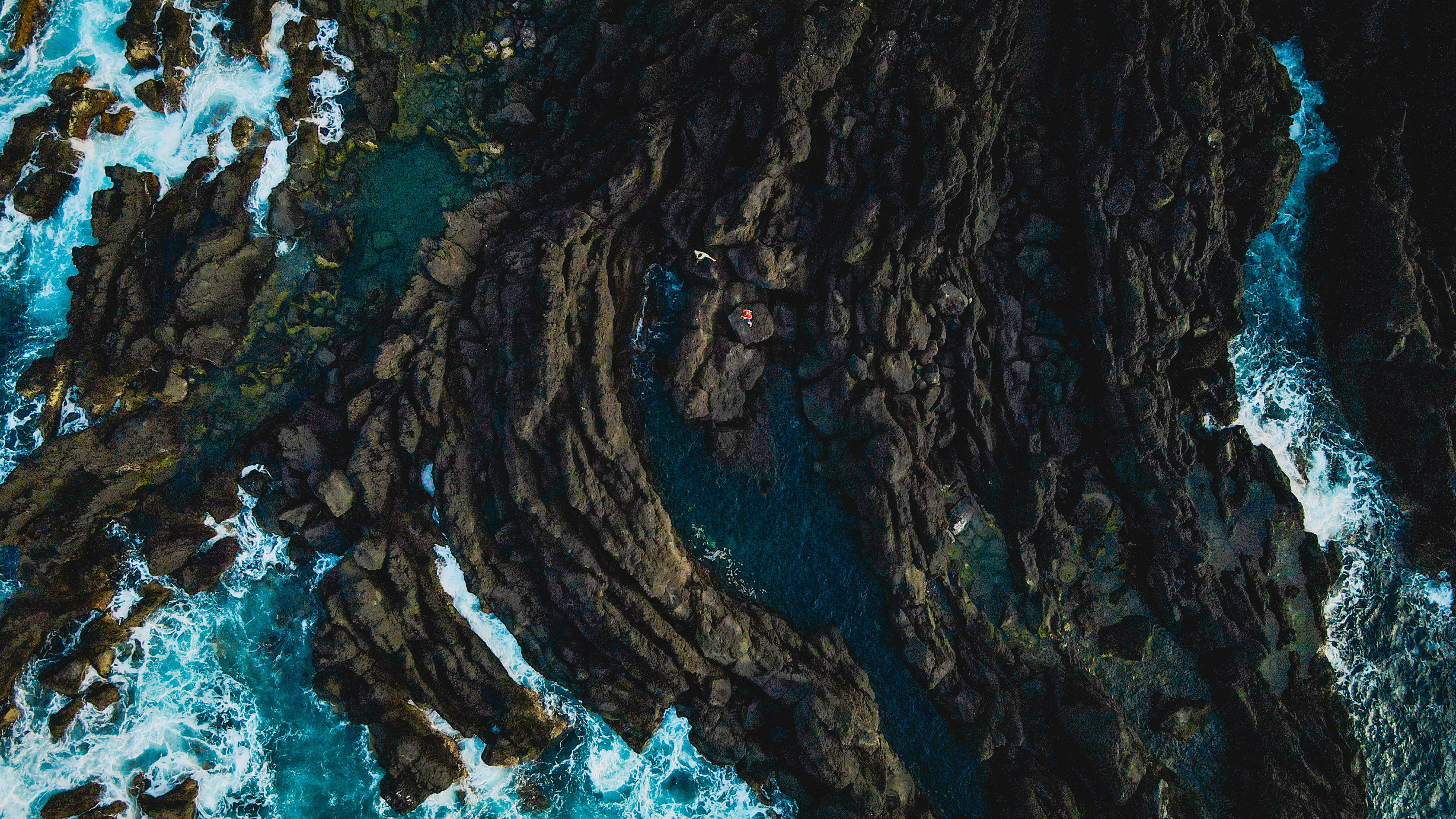 an aerial view of the ocean and rocks